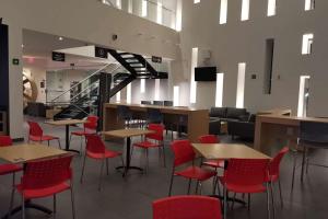 a restaurant with red chairs and tables and a staircase at Ramada Encore by Wyndham Guadalajara Aeropuerto in Guadalajara