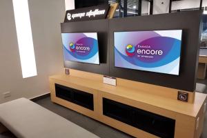two flat screen televisions on top of a wooden stand at Ramada Encore by Wyndham Guadalajara Aeropuerto in Guadalajara