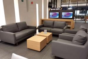 a living room with couches and a table and televisions at Ramada Encore by Wyndham Guadalajara Aeropuerto in Guadalajara