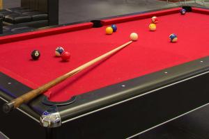 a red felt pool table with a cue and balls at Ramada Encore by Wyndham Guadalajara Aeropuerto in Guadalajara