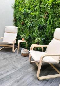 twee stoelen en een tafel voor een groene muur bij Casa do Gaspar in Aveiro
