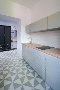 a kitchen with white cabinets and a tiled floor at Powiśle 4 by Homeprime in Krakow