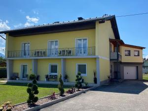 Cette maison jaune dispose d'un balcon et d'une cour. dans l'établissement Holiday apartment in St Kanzian on Lake Klopein, à Srejach