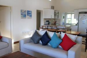 sala de estar con sofá y almohadas coloridas en T1 Goose Valley with Sea View, en Plettenberg Bay