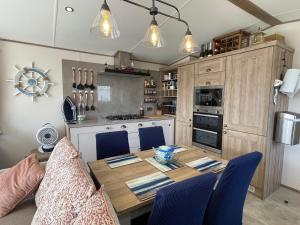 uma cozinha com uma mesa de madeira e cadeiras azuis em Caravan em Colchester