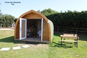 a small wooden tent in the grass with a bench at Lanterns Shepherds Huts & Glamping in Happisburgh