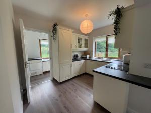 a kitchen with white cabinets and a counter top at No 2 Ardnagashel Woods in Ballylickey