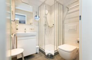ein Bad mit einer Dusche, einem WC und einem Waschbecken in der Unterkunft Arcus Hotel München Messe in Feldkirchen