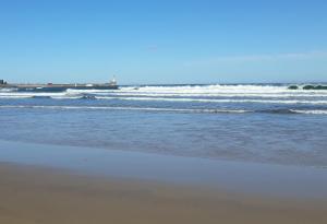 a beach with waves in the ocean on a sunny day at Paula's Cottage in New Pitsligo