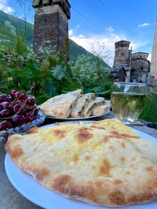 twee borden eten op een tafel met glazen wijn bij Nizharadze's Tower in Ushguli