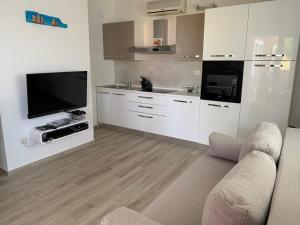 a living room with a couch and a tv and a kitchen at Apartman Demi in Miškovići