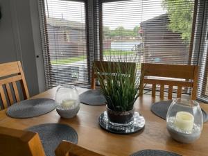 een houten tafel met twee kaarsen en een plant erop bij Lakeside 18 in Warton