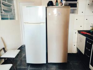 a white refrigerator in a kitchen next to a chair at Hostel Dona Lucia in São José dos Campos