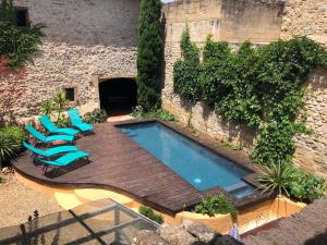 een buitenzwembad met stoelen en een terras bij La maison du Barry in Collias