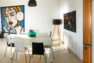 a dining room with a white table with chairs and a painting at Arthouse Surf Ericeira in Ericeira