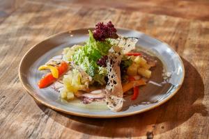 a plate of food with vegetables on a wooden table at PortoBay Falesia in Albufeira