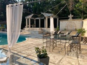 eine Terrasse mit einem Tisch und Stühlen neben einem Pool in der Unterkunft Gîte Comme à la maison in Hyères