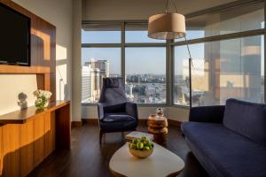 un salon avec un canapé bleu et une grande fenêtre dans l'établissement Novotel Jeddah Tahlia, à Djeddah