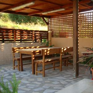 a wooden table and benches under a wooden pergola at Cretan Utopia Maisonette in Kavrokhórion