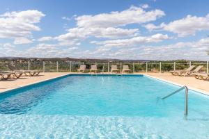 a large swimming pool with lounge chairs at Quinta da Capelinha Agroturismo in Tavira