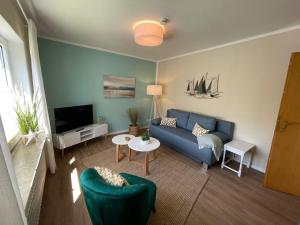 sala de estar con sofá azul y TV en Lüttje Najade Ruhige, zentrale Lage am Rande des Kurparks. Wenige Gehminuten zum Strand und in die Innenstadt. Neu renovierte und liebevoll eingerichtete Wohnung. en Borkum