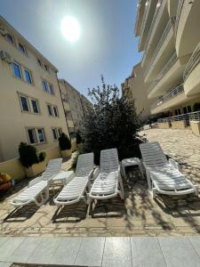 a group of white lounge chairs and a table at Coco apartments in Petrovac na Moru