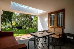 d'une terrasse avec une table, des chaises et une fenêtre. dans l'établissement StayVista's Villaggio - Orchard Oasis with Pool, Expansive Lawn, Patio & Indoor Activities, à Nashik