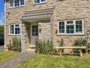 uma casa de pedra com um banco à frente em West Lulworth Apartment em Wareham