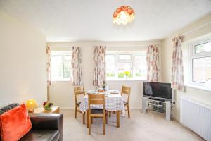 uma sala de estar com uma mesa e uma televisão em West Lulworth Apartment em Wareham