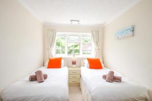 two twin beds in a room with a window at West Lulworth Apartment in Wareham