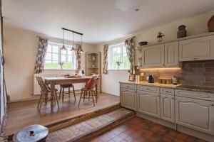 a kitchen with white cabinets and a table with chairs at Plum Pudding Cottage by Bloom Stays in Hernehill