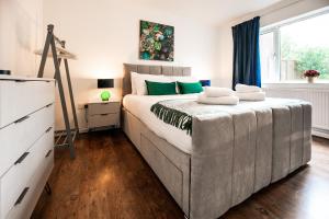 a bedroom with a large bed with green pillows on it at Beech Road Apartment St Albans by PAY AS U STAY in St. Albans