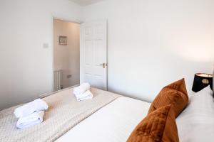 ein Schlafzimmer mit einem weißen Bett und Handtüchern darauf in der Unterkunft Beech Road Apartment St Albans by PAY AS U STAY in St Albans