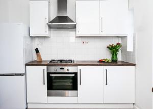 a kitchen with white cabinets and a stove at Beech Road Apartment St Albans by PAY AS U STAY in St. Albans