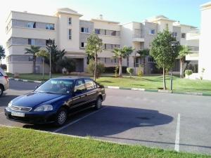 ein blaues Auto, das vor einem Gebäude parkt in der Unterkunft Appartement Bella Vista in Bouznika