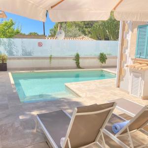 a pool with two chairs and a table and an umbrella at VILLA HERDAIN in Cielo de Bonaire 