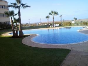 a large swimming pool with palm trees in front of a building at Appartement Bella Vista in Bouznika