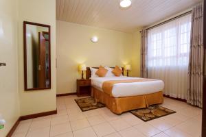 a bedroom with a large bed and a large window at The Cycads Suites in Nairobi