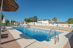 a swimming pool at a resort with an umbrella at Apartamentos El Palmeral in Conil de la Frontera