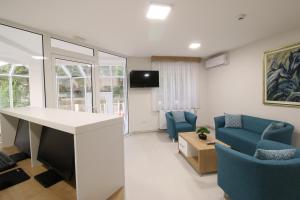 - un salon avec une table et deux chaises bleues dans l'établissement Grand Park rooms & apartments, à Čačak