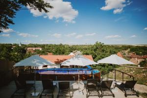a group of chairs and umbrellas with a pool at Buzás Pince Vendégház in Ecséd
