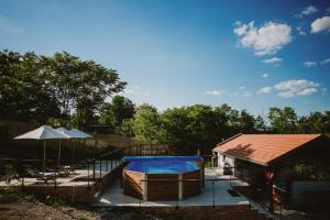 a swimming pool next to a building with a house at Buzás Pince Vendégház in Ecséd