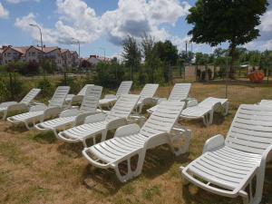 a group of white lawn chairs sitting in the grass at OWR Piramida 2 in Darlowko
