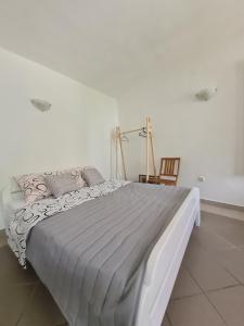 ein weißes Bett in einem weißen Zimmer mit einem Stuhl in der Unterkunft Dream House Rajic in Trpanj