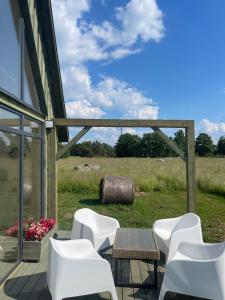 a patio with white chairs and a table and a field at Laukbaloži Holiday houses in Jūrkalne