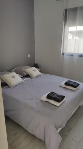 un grande letto bianco con sopra asciugamani di Jolie petite maison à 50 mètres de la plage a Cap d'Agde
