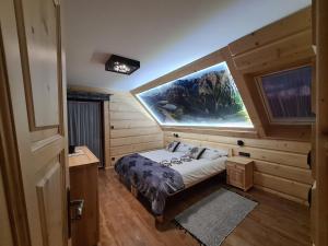 Un dormitorio con una cama y una ventana grande. en Domek u Jarząbków, en Ciche