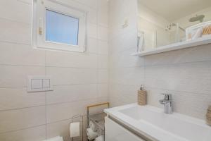 a white bathroom with a sink and a window at Apartment Stella di Mare in Krk