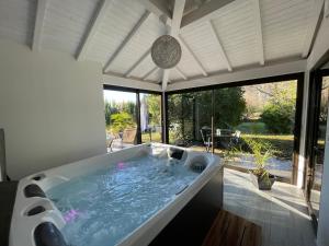 una vasca da bagno in una stanza con una grande finestra di Villa KIKO Spa & Sauna privatifs Gîte proche Sarlat a Vitrac
