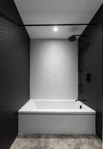 a white bath tub in a bathroom with black tiles at Luxurious Chalet with Pool, Sauna, Spa & Amazing View in La Malbaie